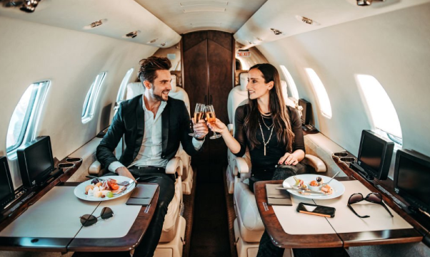 Rich couple making a toast with champagne glasses aboard a private jet. The couple living a luxury lifestyle after saving money.