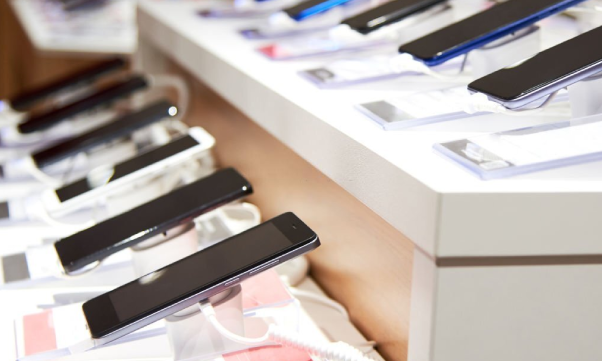 The smartphones are on the counter of a modern electronics store.
