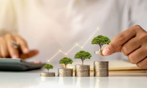 A businessman holding a coin with a tree that grows implies investment.