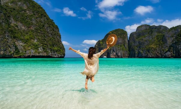 Young woman traveler relaxing and enjoying at the beautiful tropical white sand beach at Thailand,