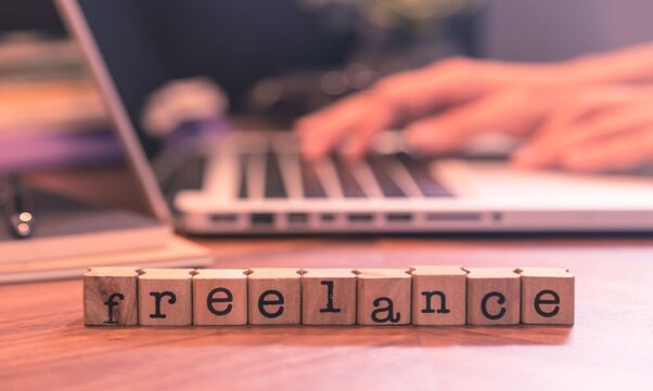 A "freelance" written in a word block in front of a laptop.