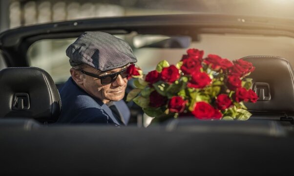 A Sugar Daddy with Roses While Seating in a Convertible Car.