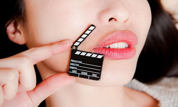 A woman with sensual lips, no eyes, with hand holding little movie clapper board