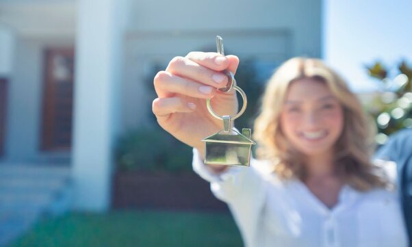 Young woman holding the key to her new house.