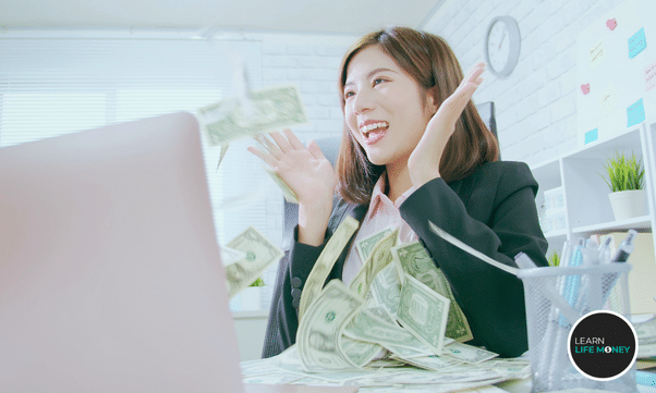 A girl with lots of dollar bills in front of her laptop.