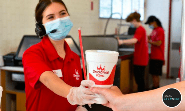 An employee giving a smoothie king drink.